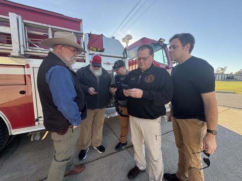 Fire Chief, Mayor, and Police Chief looking at the BoCC skycam on their phones